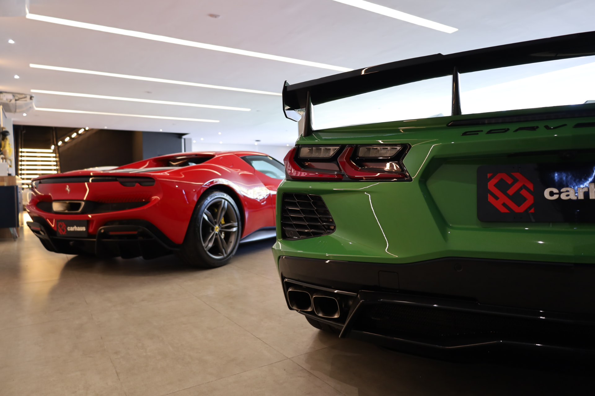 Showroom Carhaus com Corvette verde e Ferrari vermelha em exposição