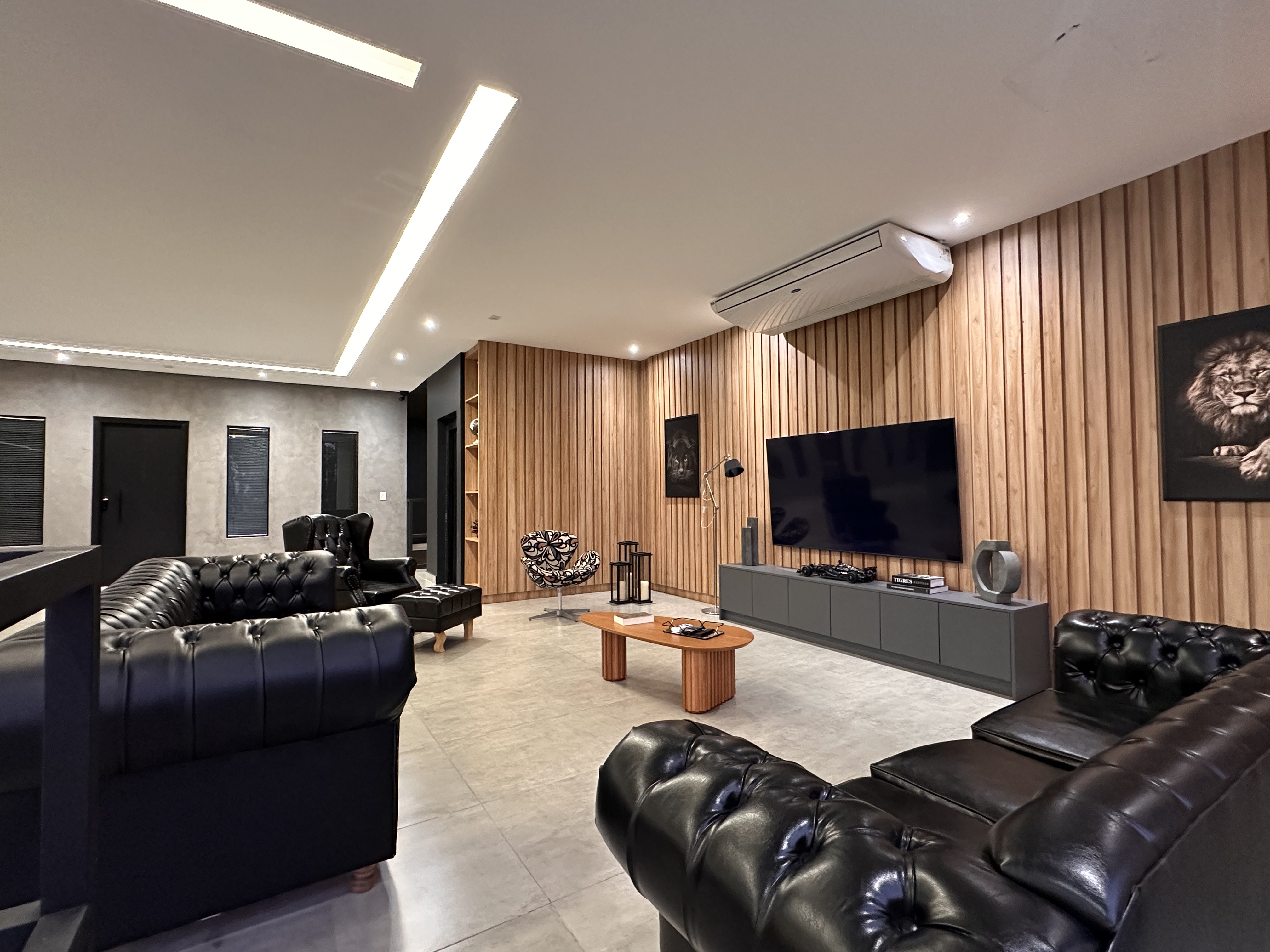Sala de estar da Carhaus com sofás de couro e painel ripado